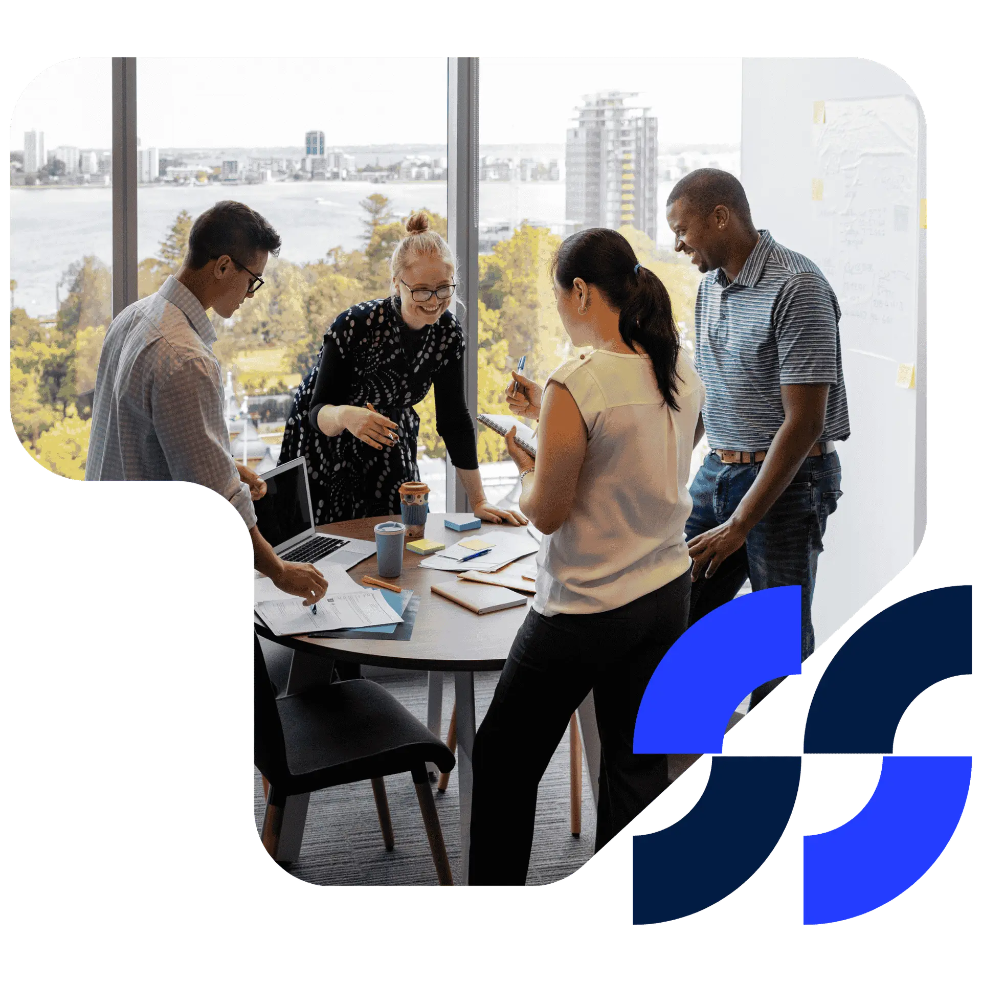 A diverse business team discusses project ideas in a modern office with city and waterfront views in the background.