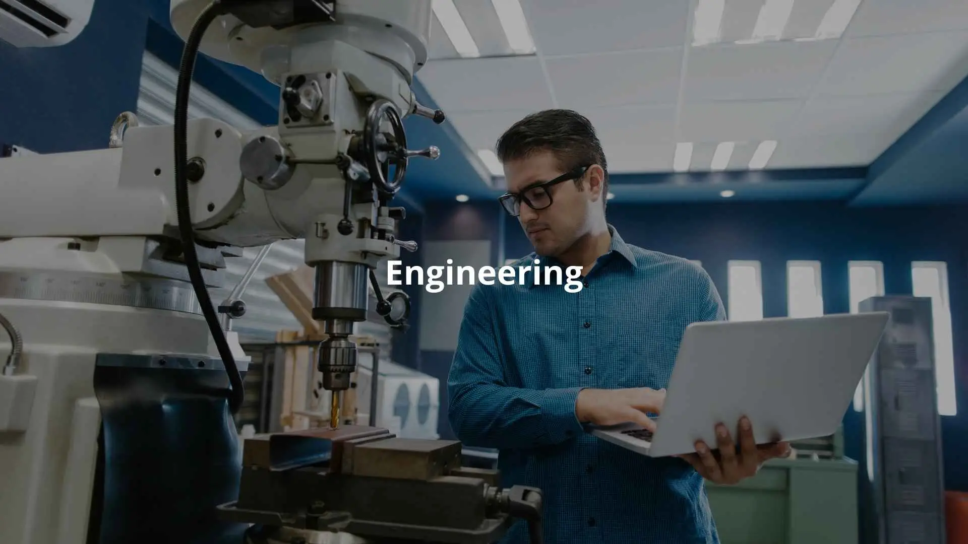 An engineer inspects a machine while using a laptop for calibration in a workshop.