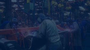 welders in protective gear performing welding tasks in a busy manufacturing facility.